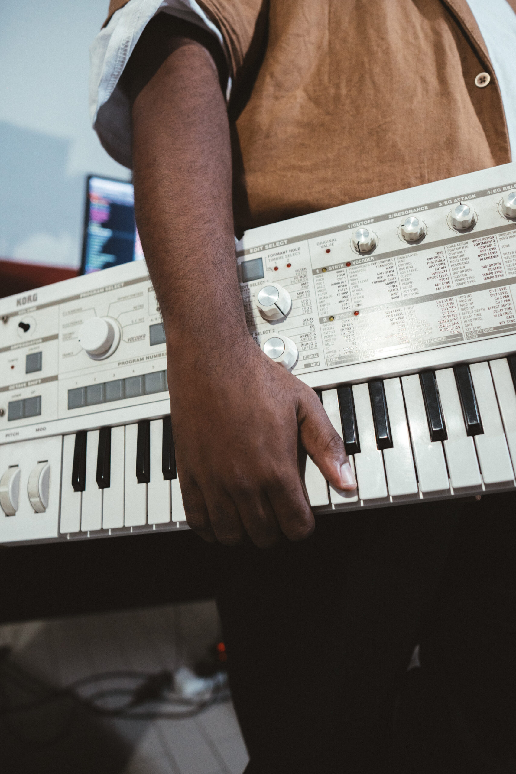Student programming drum patterns on a MIDI pad controller at a warm wooden desk